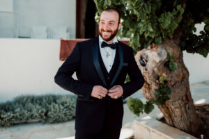 groom buttoning a button on his jacket