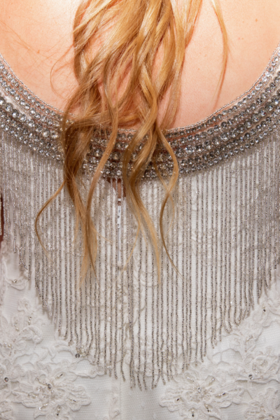 BRIDE WEARING A SPARKLY GOWN WITH A RHINESTONE FRINGE CAPLET IN THE BACK