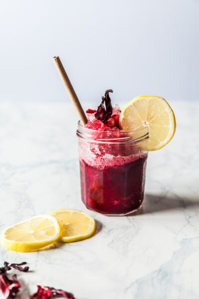 magenta cocktail with a straw and lemon accents