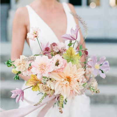 Bride carrying bridal bouquet of dahlias, clematis, roses and cqarnations