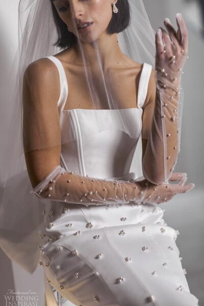 model wearing wedding veil, gown and sheer gloves studded with pearls