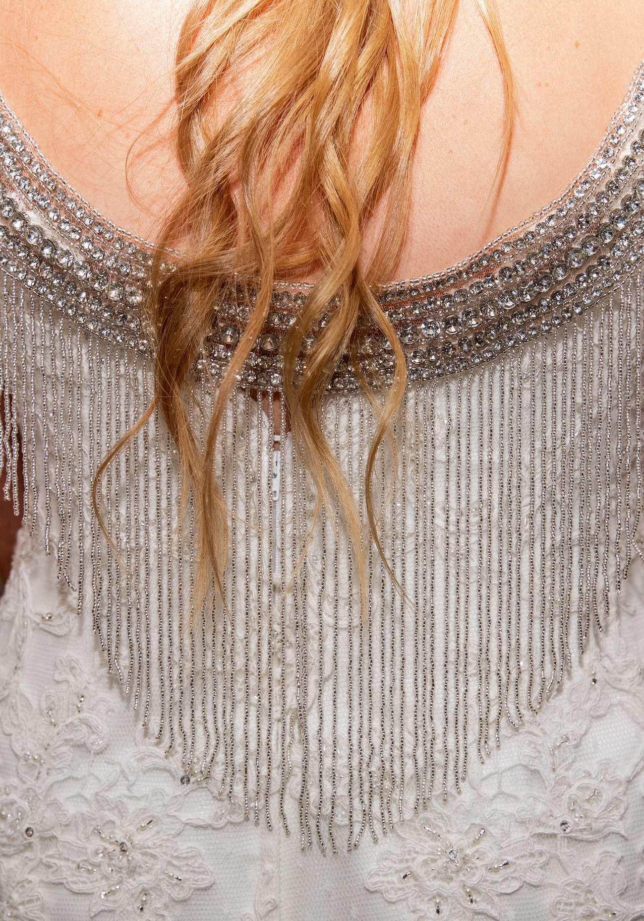 BRIDE WEARING A SPARKLY GOWN WITH A RHINESTONE FRINGE CAPLET IN THE BACK